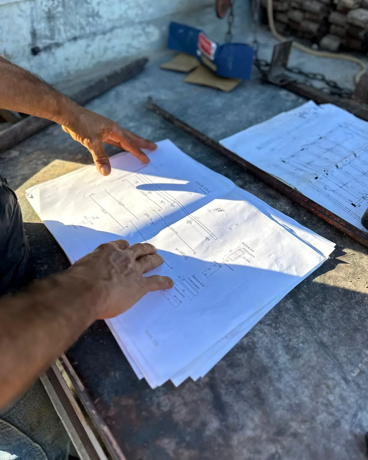 Hands spreading out printed building plans on a site table